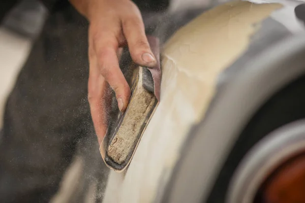 有人看到一个人的手在用木块和褐色砂纸给一辆老式汽车打沙 汽车在修复过程中的手工干砂化 即从车体上去除油灰的过程 — 图库照片