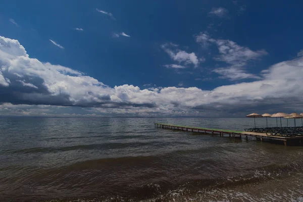 Ein Kleiner Holzsteg Führt Ins Blaue Meer Einige Reetgedeckte Regenschirme — Stockfoto