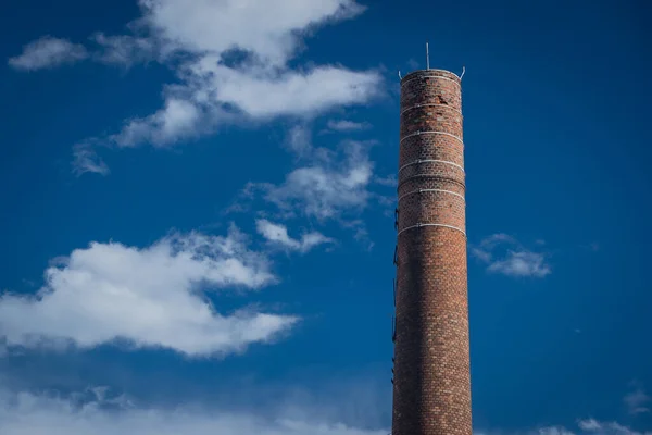 阳光灿烂的日子里 高高的砖头环绕着工业烟囱 蓝天作为背景 点缀着一些浮肿的白云 — 图库照片