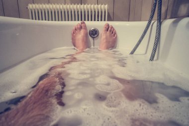 Küvette sabunlu su ve kabarcıklarla dolu kıllı erkek bacakları..