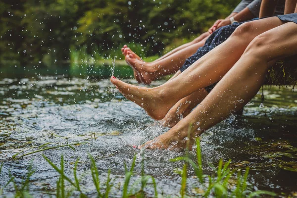 木製の桟橋でリラックスし 冷たい水に足を振りかける素敵な爪を持つ3人の若い女性の詳細 絵のようにきれいな湖に女性が水に足をはね — ストック写真