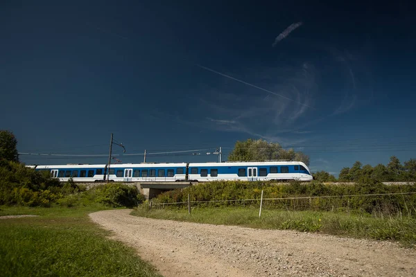 ウディネ トリエステ リュブリャナ間を走る白と青の旅客列車は 晴れた日に小さな橋を渡ってプレスリェ駅に近い — ストック写真