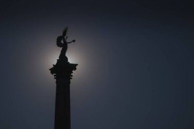 Macaristan 'ın Budapeşte kentindeki Heroes Meydanı' ndaki Milenyum anıtının siluet fotoğrafını kapatın. Mimari element güneşli bir sonbahar gününde gün ortası güneş tarafından aydınlatılır..