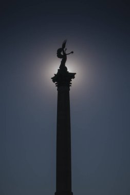 Macaristan 'ın Budapeşte kentindeki Heroes Meydanı' ndaki Milenyum anıtının siluet fotoğrafını kapatın. Mimari element güneşli bir sonbahar gününde gün ortası güneş tarafından aydınlatılır..