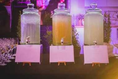 Bir etkinlikte çay, su, limonata ya da buzlu çay gibi içecekler için büyük cam şişeler ya da kaplar ya da şişelerin içeriğini yazmak için boş panoların olduğu bir gala partisi..