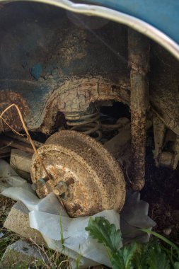 Ağır paslanmış trampet frenleri ya da terkedilmiş eski bir aracın arka dingilli ve yaylı fren davulunun dış tarafı. Eski mavi bir arabanın tekeri kayıp..