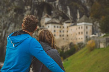 Romantik çift Slovenya 'da güzel bir Predjama kalesini izliyor. Uçurumun kenarındaki büyüleyici kaleye romantik seyahat kavramı. Aşıklar romantik bir manzarayı gözlemliyor..