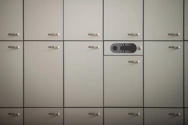 Frontal close up of many lockers or metal or wooden lock boxes. Lockers with numbers, rfid codes and round knobs. visible main part with electrical lock.
