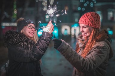 Ellerinde maytap olan iki genç kadın, şehrin merkezinde Noel ışıklarının altında bir akşam geçiriyorlar. Soğuk kış atmosferi ve şehir dışında keyif..