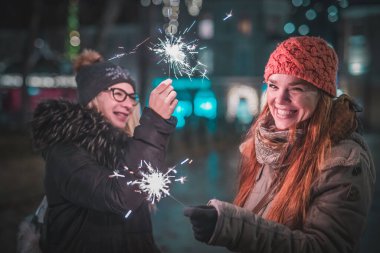 Ellerinde maytap olan iki genç kadın, şehrin merkezinde Noel ışıklarının altında bir akşam geçiriyorlar. Soğuk kış atmosferi ve şehir dışında keyif..