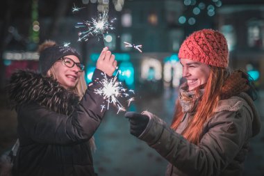 Ellerinde maytap olan iki genç kadın, şehrin merkezinde Noel ışıklarının altında bir akşam geçiriyorlar. Soğuk kış atmosferi ve şehir dışında keyif..