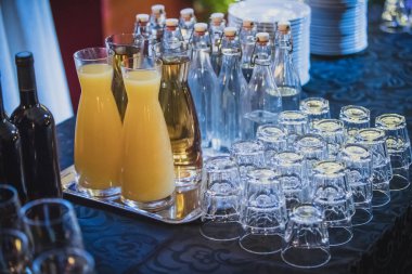 Masanın üzerinde renkli bir arka planı olan bardak ve şişe koleksiyonu. Kutlamaya hazır kadehler bir gala ya da partinin ışık arka planında,