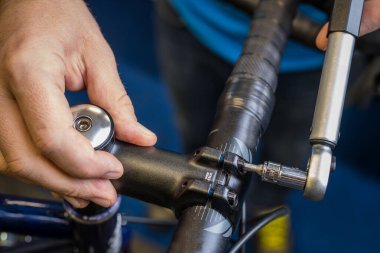 Tightening of a bicycle handlebar stem with the use of a small torque wrench. Proper way to tighten a bicycle handlebars. Bicycle service in a worshop. clipart