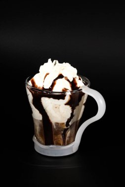 Sıcak çikolata ya da kahve bardağında koyu renkli tutacağı olan bir içecek. Görünür hindistan cevizi kırıntıları, süt, krema ve diğer tatlı malzemeler..