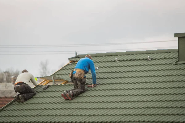 Installation of a domestic solar power plant. Visible workers on the roof preparing fixation points and opening parts of the roof for solar panels for a home power plant.