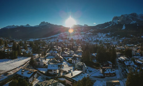 Aerial drone panorama of the alpine dolomite city of Cortina d\'Ampezzo just before sunset on a sunny day in january, looking towards Tofana.