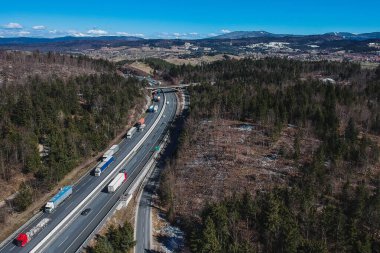 Otoyolda ya da otoyolda trafik sıkışık. Ülkenin üzerinde bir trafik sıkışıklığında sıkışmış kamyon veya kamyonların insansız hava aracı fotoğrafı. Otobanda uzun bir römork kuyruğu