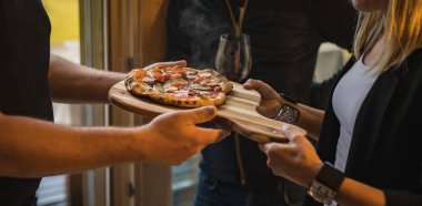 Bir erkek ve bir kadın yeni bir ev alışverişi yapıyorlar İtalyan usulü pizzayı bir kutlama hediyesi olarak yapıyorlar. Hediye olarak sıcak pizza.