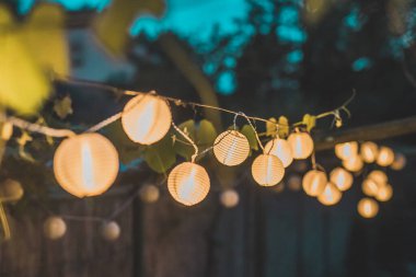 Geceleri ahşap sazdan bir arka planda ev bahçesinde yuvarlak kağıt fenerler. Bir akşam bahçede şenlik dekorasyonu..