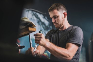 Profesyonel tamirci vidayı gevşetmek için anahtarı kullanarak dış motoru tamir ediyor. Süslü bir atölyede tekneyi tamir eden adam.