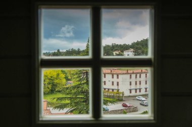 Slovenya 'nın Stanjel kentinin panoraması bulutlu bir bahar günü, üzerinde ahşap bir haçla pencereden bakıyor..