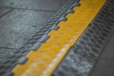 Yerde siyah ve sarı plastik kablo koruyucu var. Plastik kaplı zemin koruyucusu. Yüksek görünürlük renklerinde bir olay için kablo kaydedici.