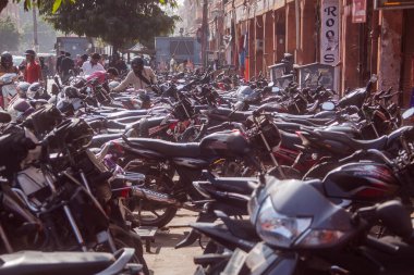 JAIPUR, INDIA, 2.12.2016: Jaipur 'da bir sokağa park edilmiş çok sayıda motosiklet ve scooter. İnsanlar geçip gidiyor. Motosiklet parkı.