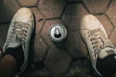 Halk parkında bira içmek, yukarıdan bir bira kutusunun iki ayak arasında durması. Öğrenci parkta parti yapıyor ve içiyor..