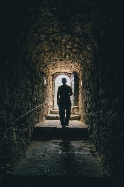 Chisinau yakınlarındaki Moldova 'daki Orheiul vechi' de oyulmuş taş bir manastırdan çıkan bir kadın. Tünelde yürüyen bir insanın ana hatları..