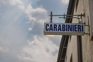 İtalyan polis kuvvetlerinin bir parçası olan Carabinieri için aydınlatılmış eski bir tabela. Tahta bir evin duvarında asılı.