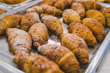 Bir gala ya da partide gümüş bir tabağa istiflenmiş bir parça kruvasan. Çikolata parçacıkları ve şekerle kaplı tatlı hamur işi ürünleri sergileniyor..