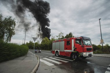 Slovenya, Ljubljana, Stegne 'de bir otoyolun yanında çıkan yangının fotoğrafı. Koyu renkli duman bulutu, ön planda kırmızı itfaiye aracının görüldüğü yerden yükseliyor..