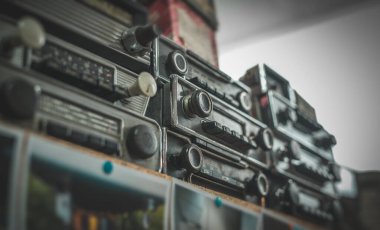 Rafa istiflenmiş eski zaman radyoları. Eski bir araba teybinin bit pazarı koleksiyonu.