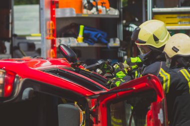İtfaiyeciler, içinde yakalanan sürücüyü kurtarmak için kaza yapan arabayı kesmek için hidrolik bir yaşam ya da makas kullanıyorlar. Trafik kazasında acil durum.