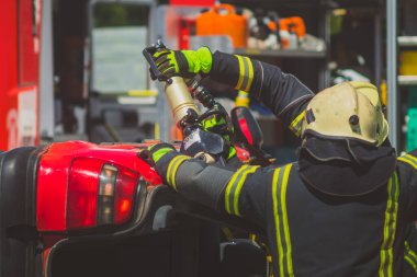 İtfaiyeciler, içinde yakalanan sürücüyü kurtarmak için kaza yapan arabayı kesmek için hidrolik bir yaşam ya da makas kullanıyorlar. Trafik kazasında acil durum.
