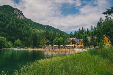 Kranjska gora 'daki Jasna' nın güzel yeşil alp gölü. Yürüyüşçüler, gezginler ve turistler için iyi bir tatil yeri. Bulutlu bir yaz gününde Alp Gölü 'nün yanında evler ve plajlar
