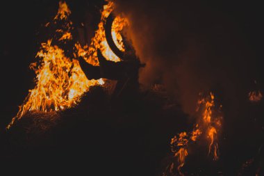 Dağ bisikletli çılgın bir bisikletçi gerçek bir etkinlikte şenlik ateşinde kıvılcımlar ve alevler içinde motorcunun yanından geçiyor. Motorcu tehlikeli bir şekilde açık ateşle oynuyor..