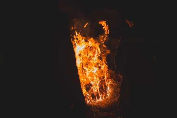 Unknown people standing around a bonfire made out of old euro palettes.