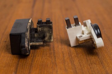 Tahta bir bankta eski ve yeni alternatör fırçaları ve regülatör karşılaştırması. Alternatör servisi için yedek parça karşılaştırması.