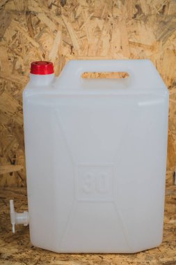 Su için beyaz plastik şeffaf bidon ve altında bir petcock görünür