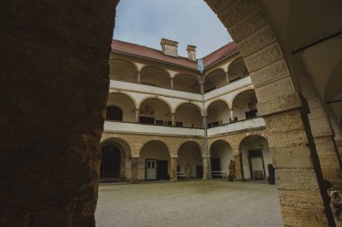 Ptuj kalesinin kemerleriyle güzel bir avlu. Sıkıcı bir sonbahar gününde Ptujski 'nin cephesi ve ana meydanı.