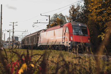 Kırmızı lokomotifli kırmızı Avrupa tarzı yük treni kapalı vagonları olan bir viraja giriyor..