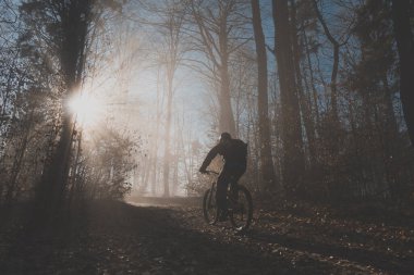 Güneş ışınlarının siste parladığı destansı bir anda tepeye, güneşe doğru çıkan tek bir dağ bisikletçisi. Efsanevi MTB sürücüsü.