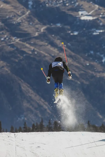 テレマーク スキーヤーは後ろにアルプスの背景で背中に向かってジャンプしていた テレマークスキーヤーのアクションショット — ストック写真