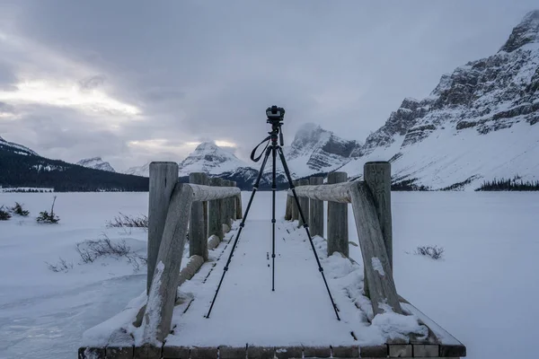 寒冷的冬季清晨 在加拿大弓湖的一座木桥上 三脚架上的照相相机 用照相相机拍摄寒冷的冬季全景 — 图库照片