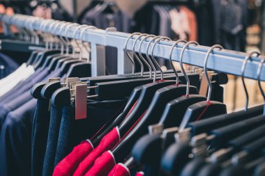 Klasik tel ve plastik askılarla bir tekstil dükkanında askıda asılı bir sürü farklı kıyafet. Dükkanda sıra sıra kıyafet..