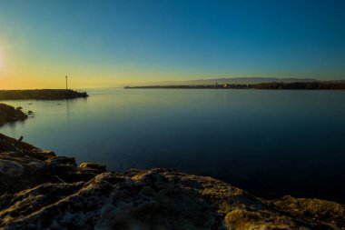 Lac Leman 'ın Lozan' a yakın güzel bir akşam fotoğrafı. Ufkun hemen üstünde güneş ve suyun uzun pozu var..