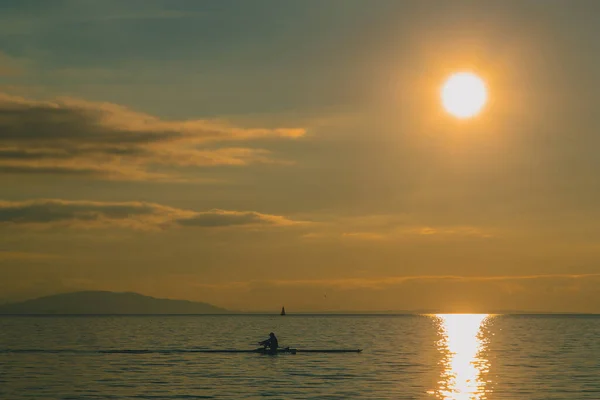カヤックや夜の時間帯に湖の上のパドルボートの人 水の上でロマンチックなレジャー活動 太陽が水に沈もうとしている — ストック写真