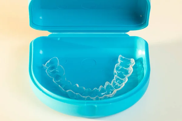 用透明的塑料制成的牙齿矫形器 装在蓝色的手提箱中 与白色隔离 牙齿对齐用固位器 — 图库照片