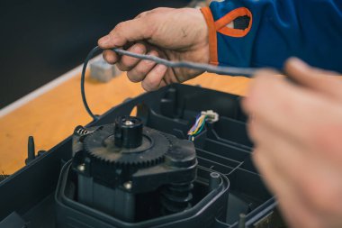 Robotik çim biçme makinesinin su foklarını değiştiren tamirci, çamurda ve çimenlerde bir yıl kullanıldıktan sonra motorlu çim biçme makinesinin bakımını yapıyor. Robot çim biçme makinesinin düzenli bakımı